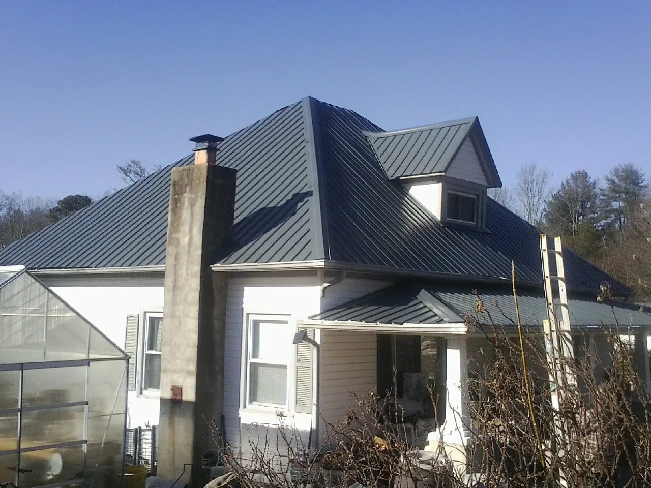 Dark blue standing seam metal roof on a white farmhouse with dormer — Slate & Tile Roof Repair by Roofing Brothers in La Grange Park