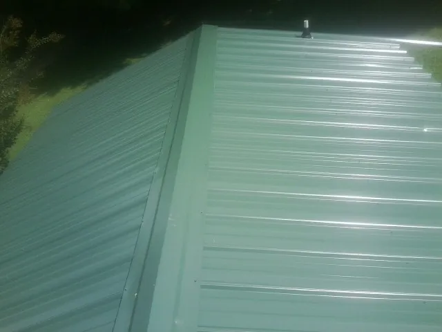 New green metal panels meeting at the ridge of a roof — Flat Roof Repair work by our crew in La Grange Park