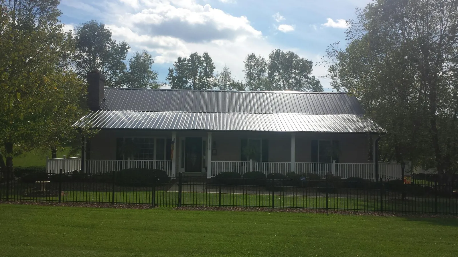 Gray metal roof on a brick ranch with a full width front porch — Gutter Guard Installation work by our crew in La Grange Park