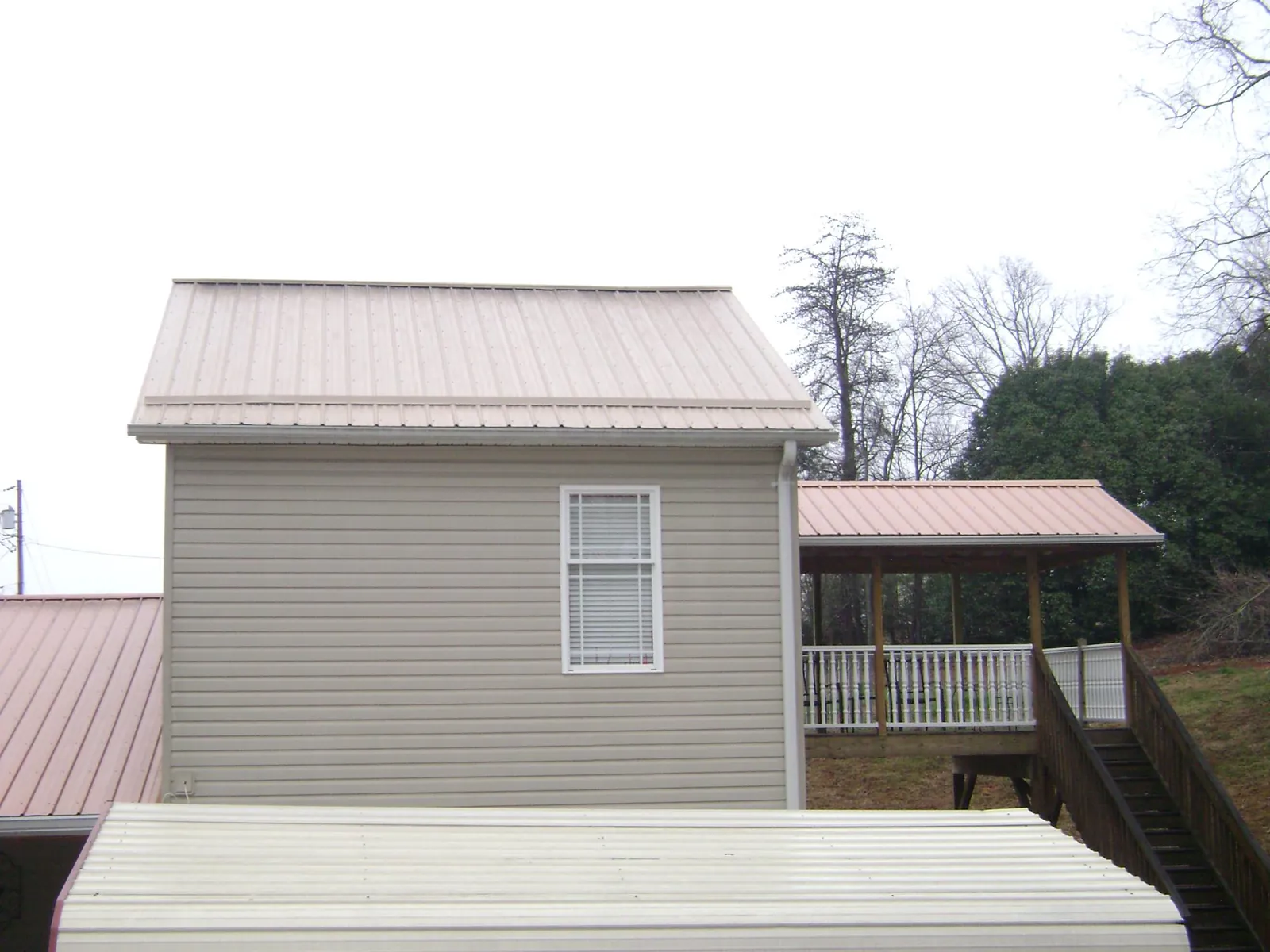Tan metal roofs on a two story addition and attached porch, from a Roof Replacement job in La Grange Park