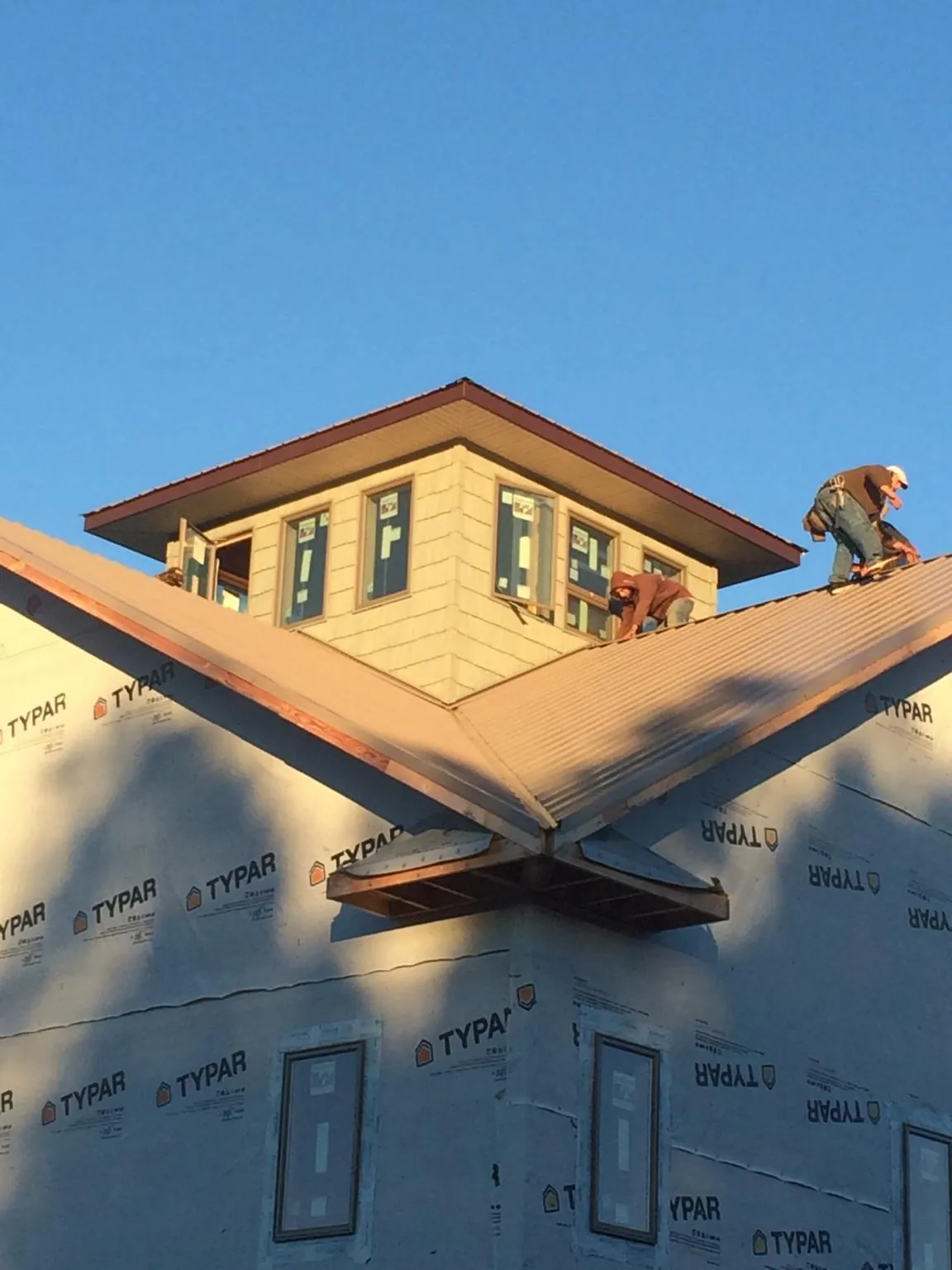 Roofers working around a rooftop cupola on a new metal roof at sunset — Roof Waterproofing in La Grange Park by Roofing Brothers